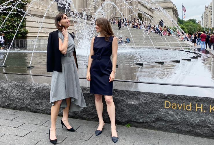 Two women with brown hair wearing business professional standing in front of The Met