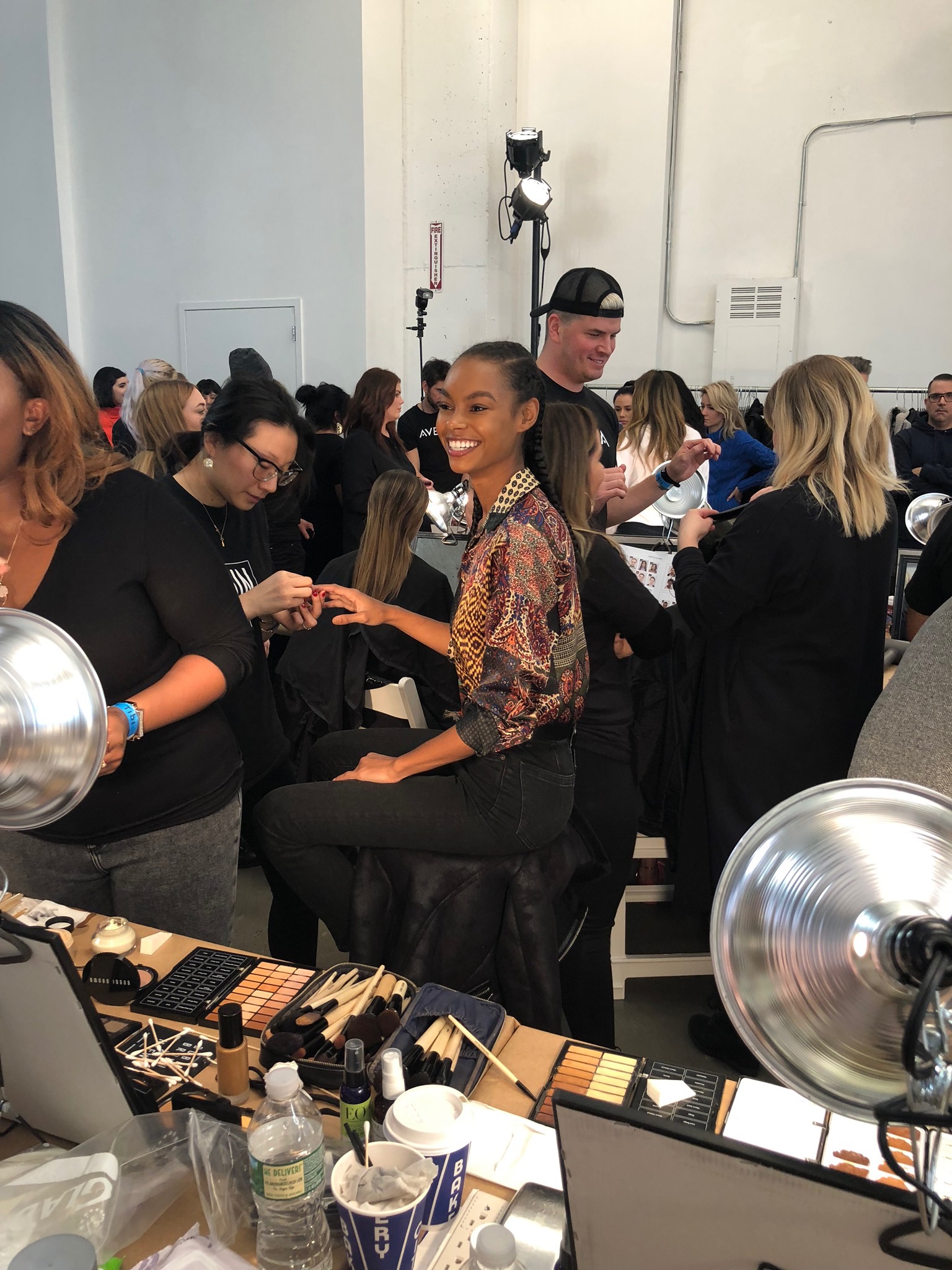 Backstage at a fashion show: a black model gets her nails done, she is smiling