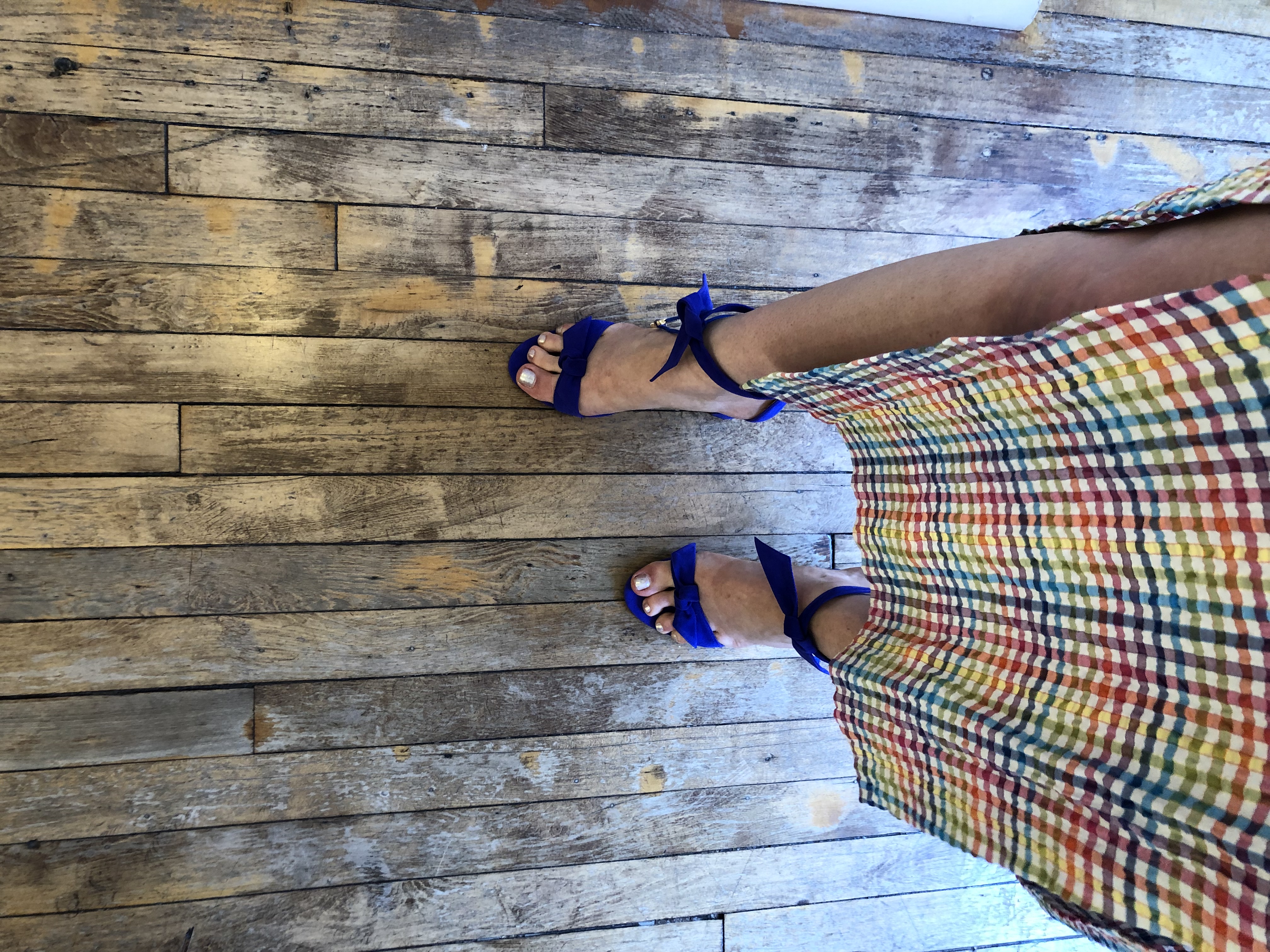 Shoefie: woman wearing a rainbow print dress and purple wedges standing on a wooden floor