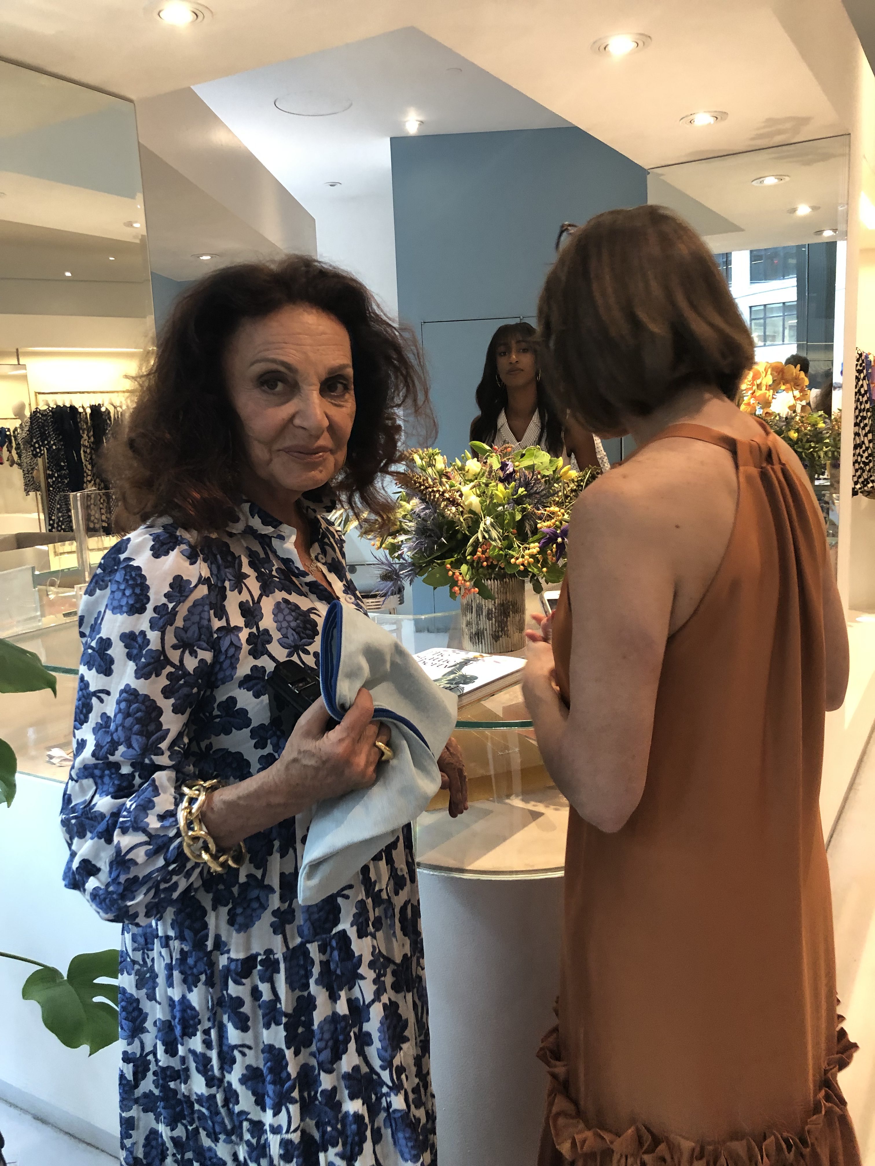 Diane von Furstenberg wearing a blue & white dress with another woman in a rust dress