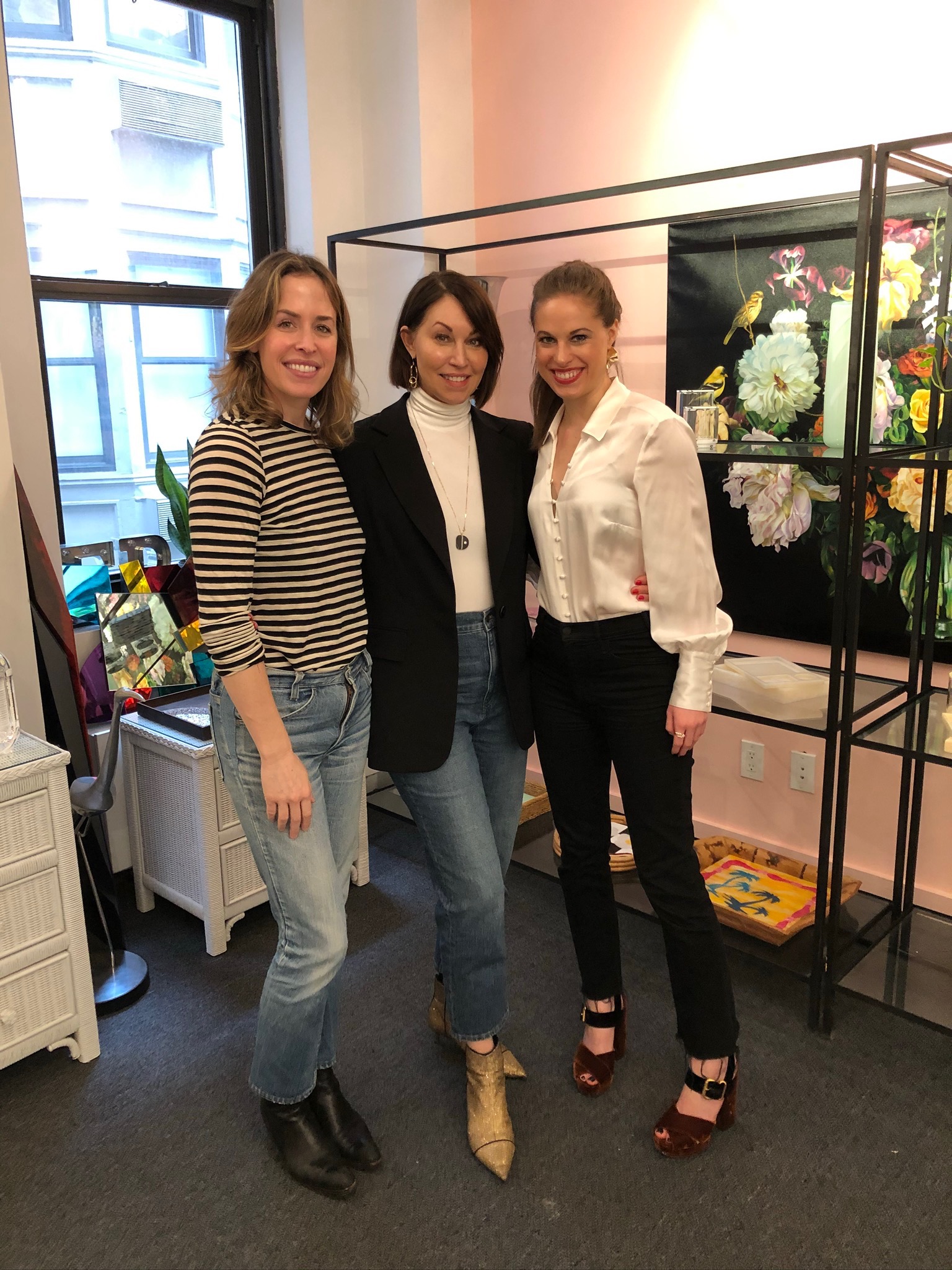Three women vertical picture. One woman in a white & black striped top, one woman in a black blazer & white bodysuit and one woman in a white silk top with velvet heels