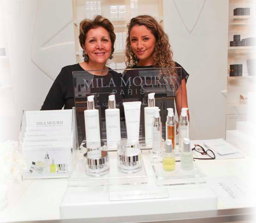 Two women: Mila Moursi and her daughter standing at a beauty counter behind the display of their cosmetics