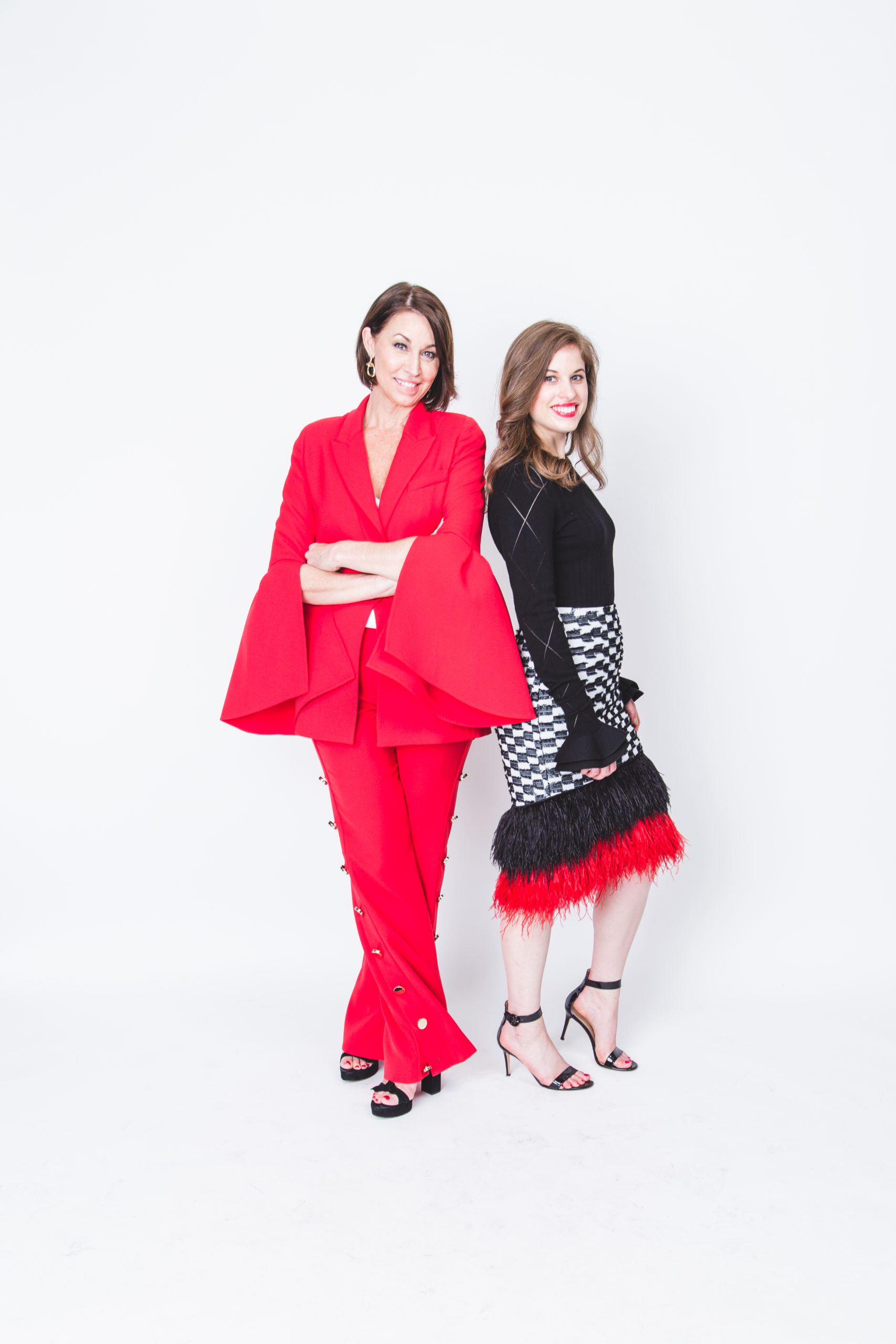 Stylish mother daughter duo dressed in red, black & white on set at a photoshoot. Wearing black heels