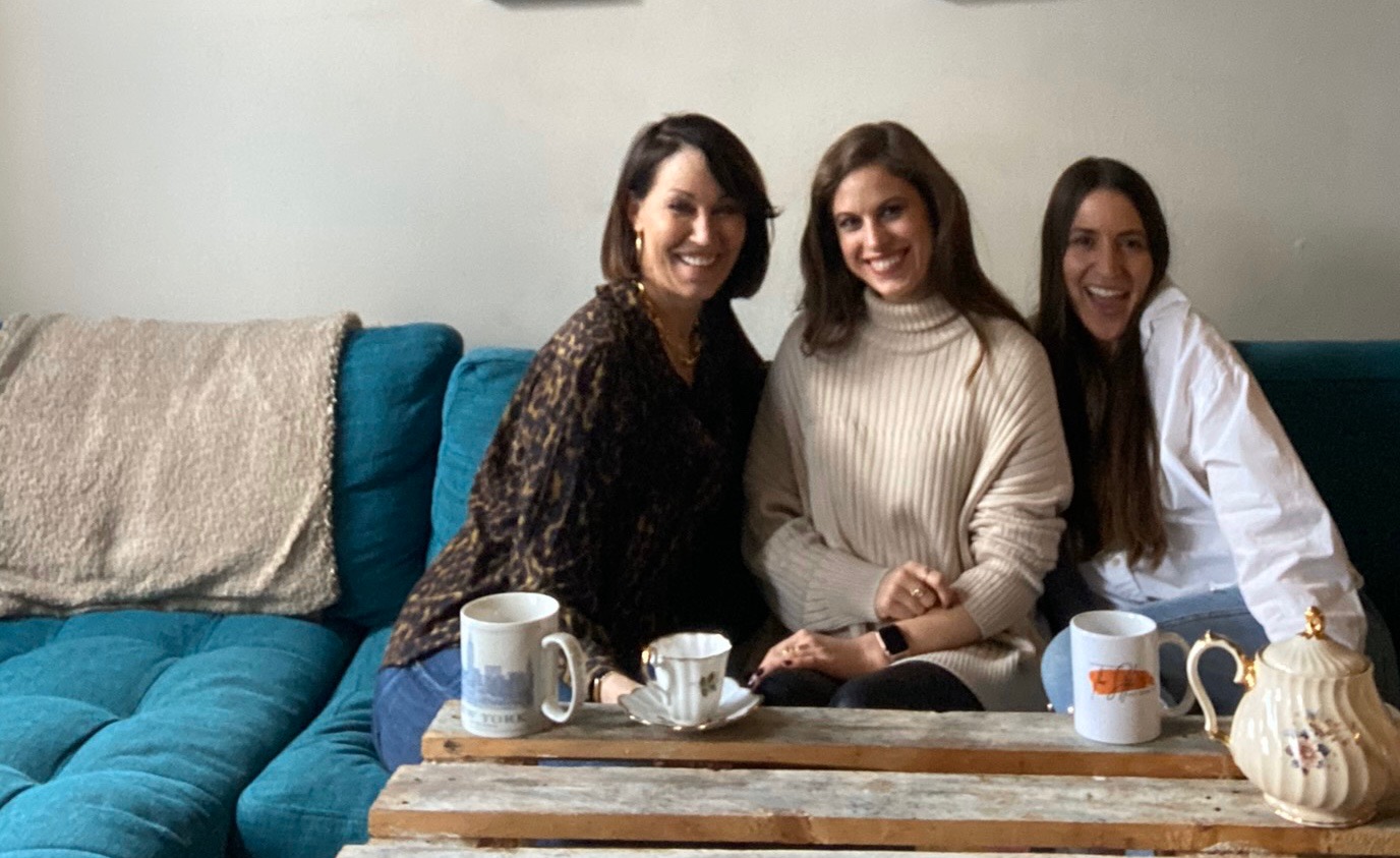 Three women (all with brown hair) sitting on a teal couch