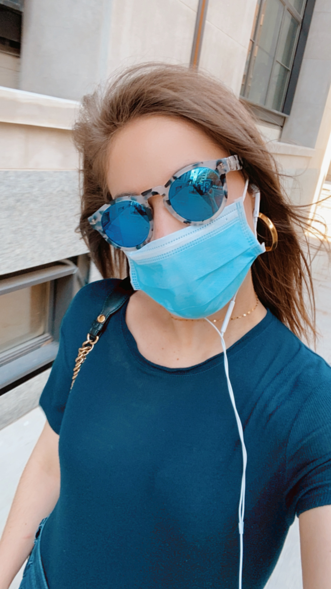 Girl with blue sunglasses, a surgical mask, headphones and a navy t-shirt