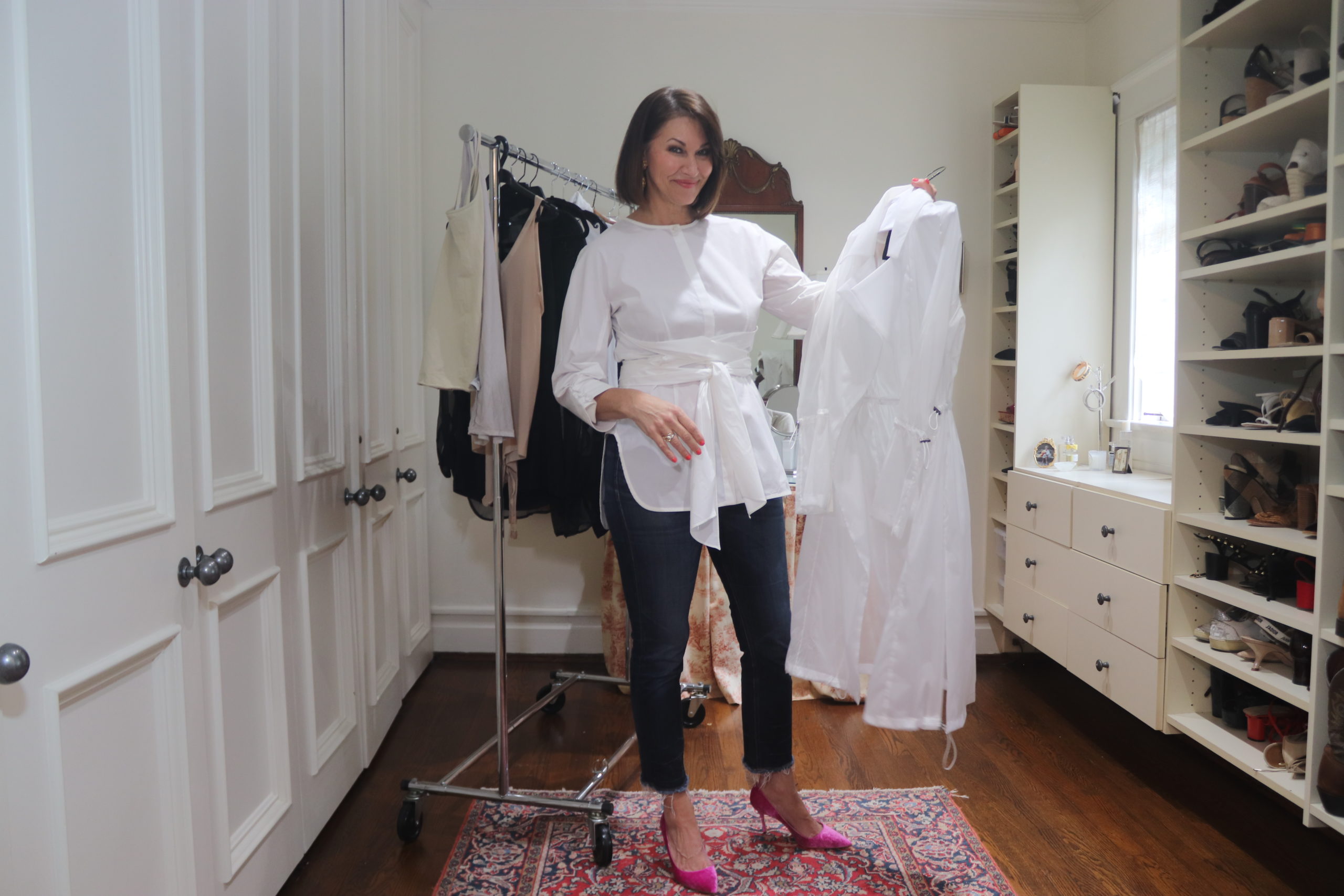 Woman wearing a white shirt, jeans and pink pumps standing in a closet