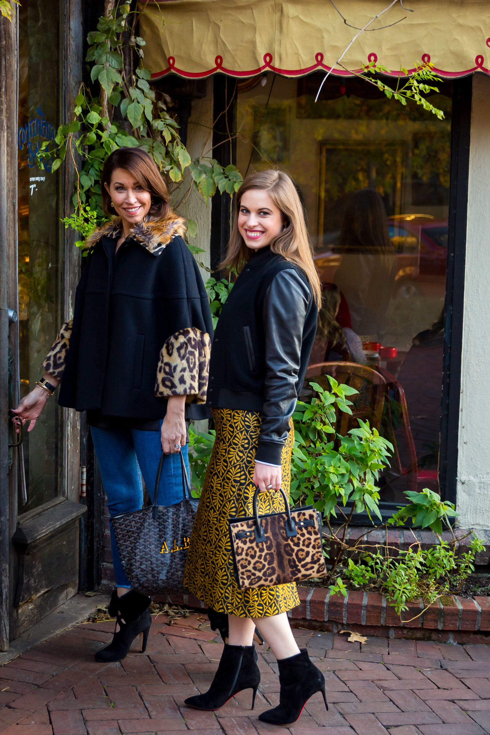 Two women with brown hair in fall outfits smiling at each other