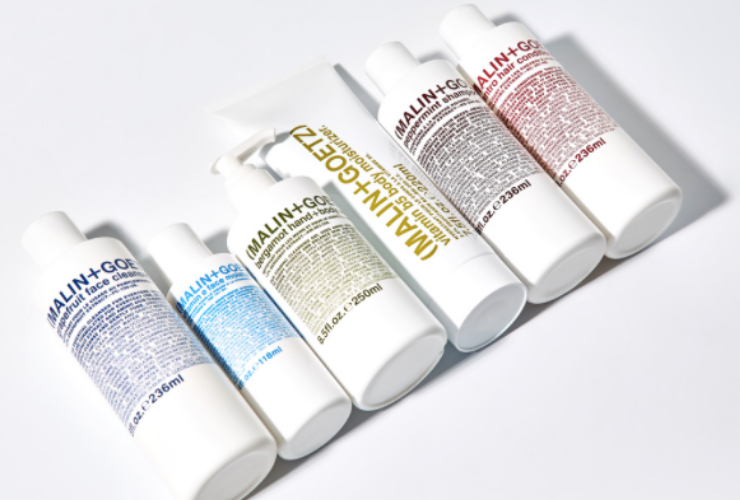6 beauty products in white bottles with rainbow colored writing on a white background