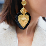 White woman with brown hair close up of her gold & black heart statement earring