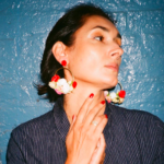 Brown skinned woman with short black hair wearing hoop statement earrings with multi-colored flowers