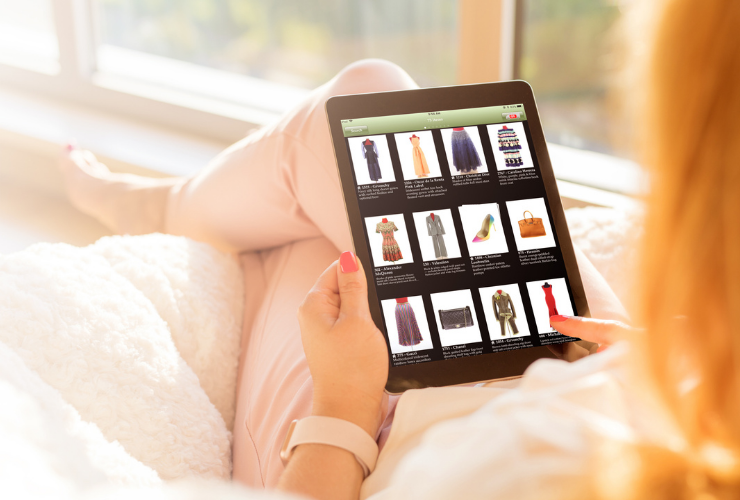 Over the shoulder view of someone looking at an iPad looking at an e-commerce site with various items of clothing, wearing light pink outfit, white woman with blonde hair