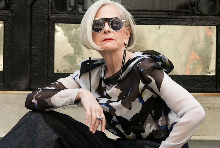 Woman with short grey hair wearing sunglasses not smiling but looking at the camera