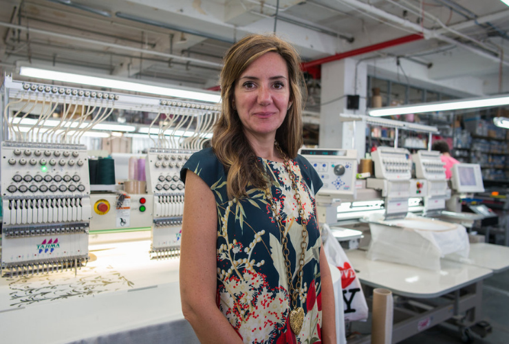 White woman with brown hair standing in a garment factory