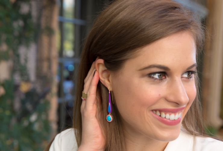 white woman with brown hair looking to the side wearing colorful drop earrings