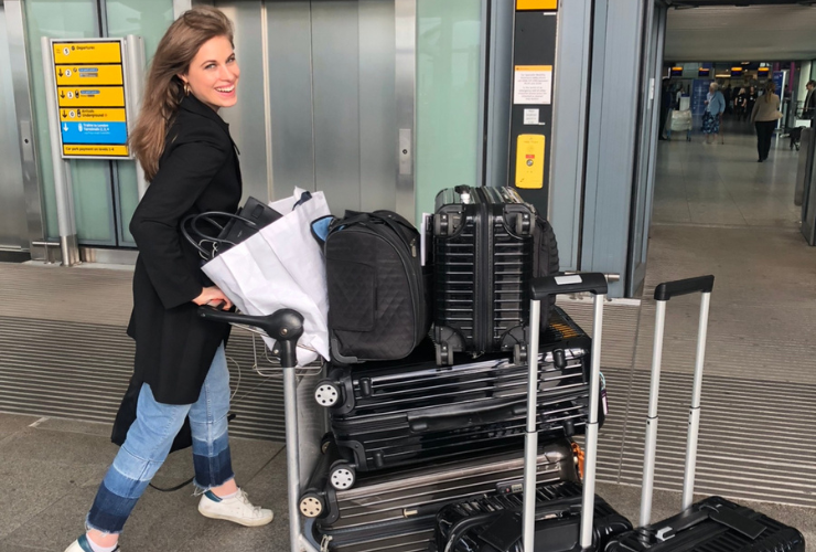 White woman with brown hair pushing a bunch of suitcases