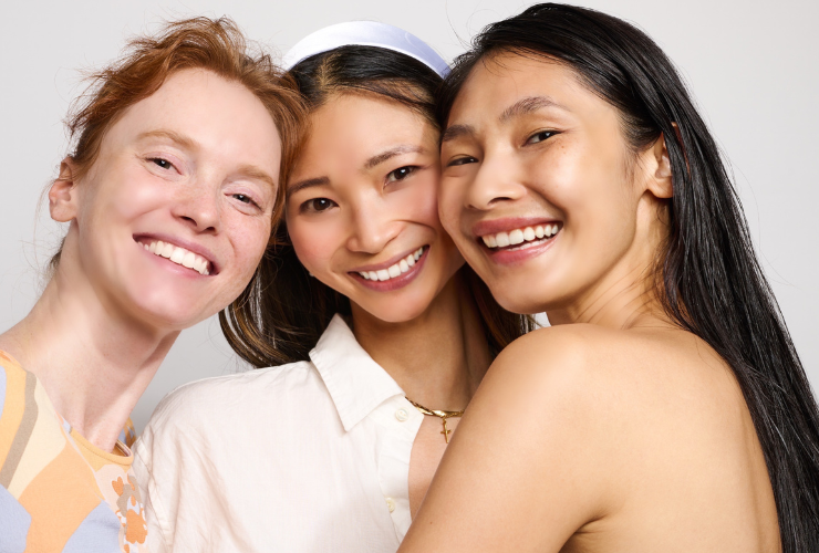 3 girls - 1 white with red hair & 2 asian girls smiling at the camera