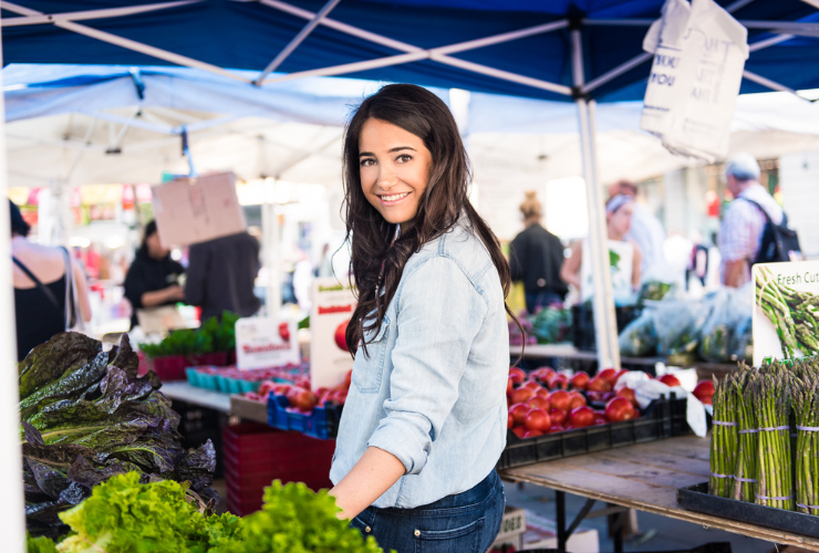 white woman with brown hair at a farmer's market wearing a denim jacket