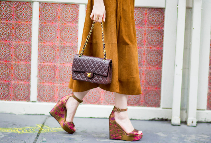 Brown Chanel Flap Handbag is the main focus - white girl with camel skirt walking holding the bag