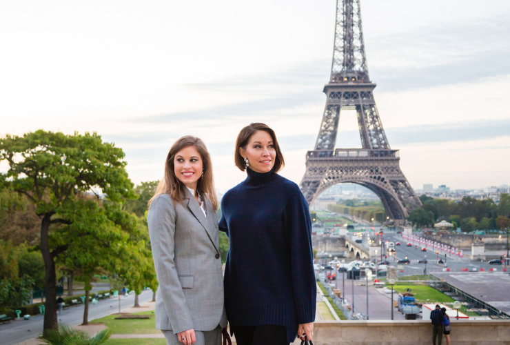 Two white women with brown hair in front of the Eiffel Tower