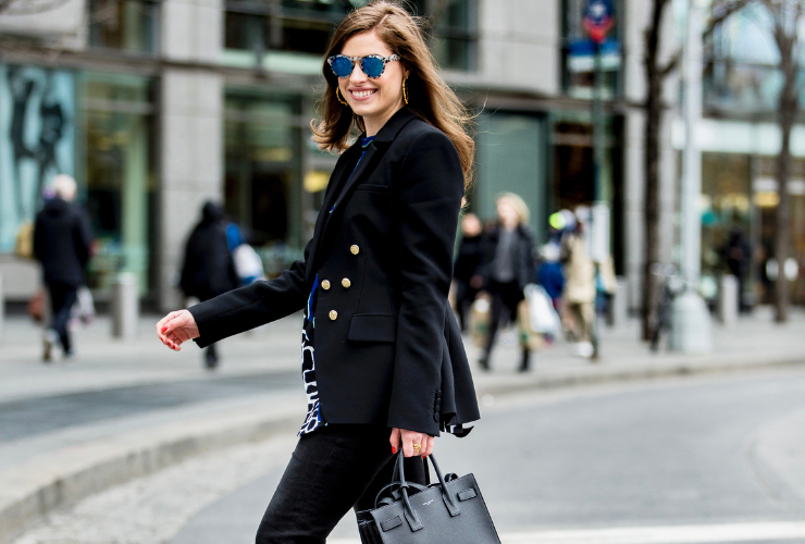 White girl with brown hair wearing sunglasses walking across a NYC street