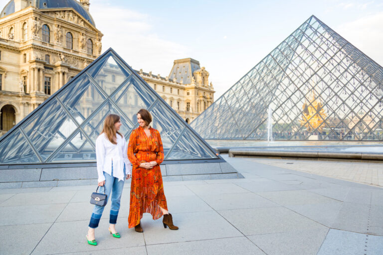 two white women with brown hair in front of the louvre